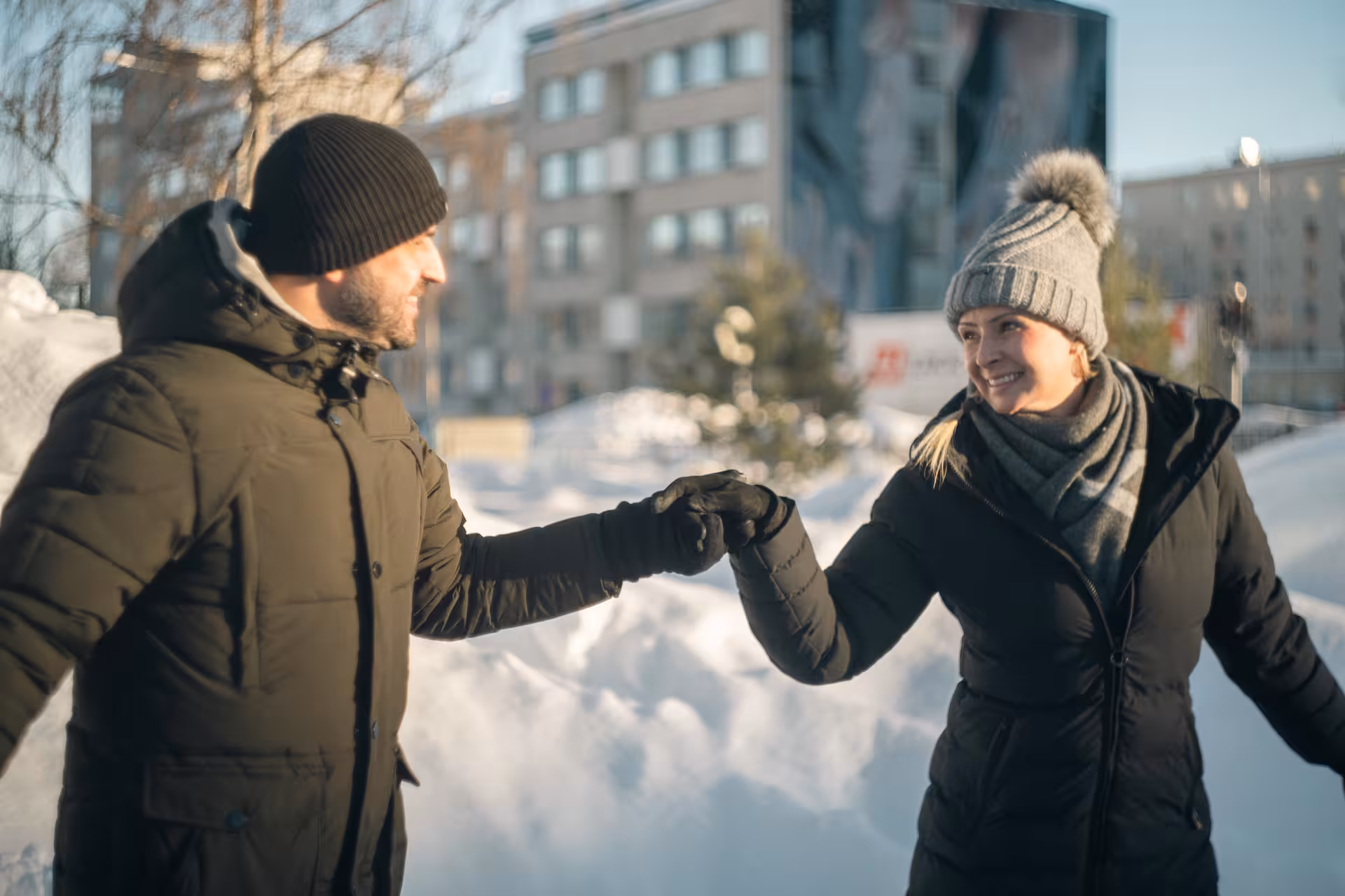 Happy couple holding hands while ice skating in Rovaniemi, capturing joyful moments in a winter wonderland.