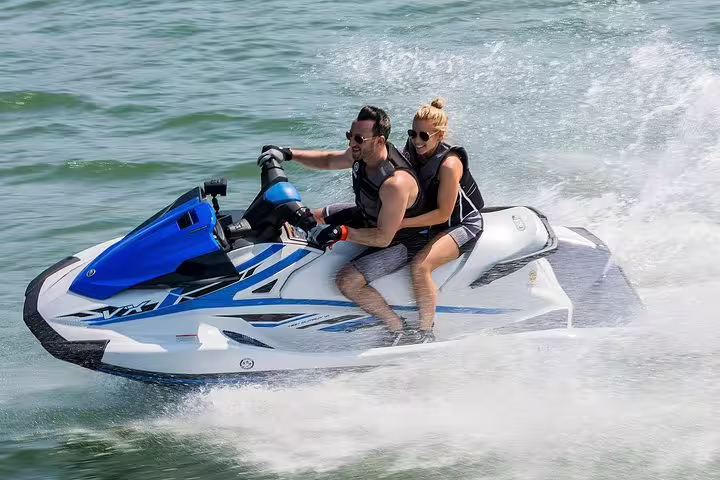 Couple riding a jet ski from San Antonio Ibiza, speeding over waves on the Margaritas Islands tour