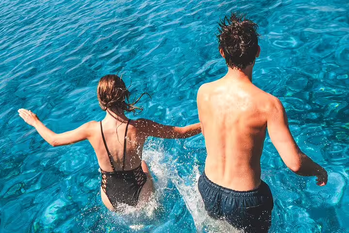 Couple jumping into turquoise Blue Lagoon water during 3 Islands speedboat tour from Split, Croatia