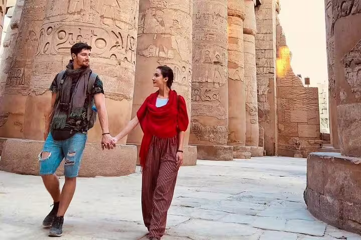 Couple walking among Karnak Temple columns in Luxor on private overnight tour from Cairo by flight, Egypt