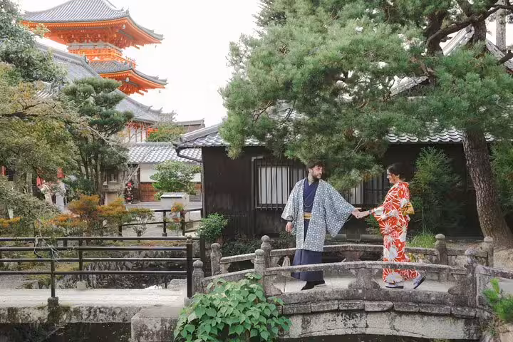 Couple in kimono on stone bridge by temple garden in Kyoto, captured during private vacation photographer shoot