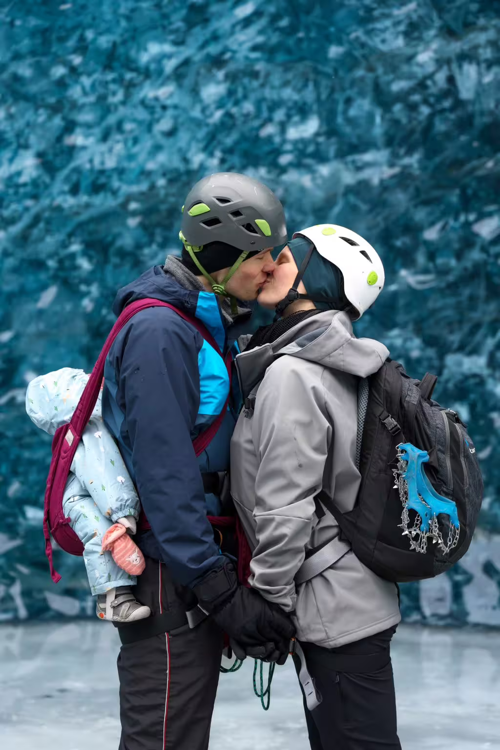 A couple sharing a romantic kiss inside a breathtaking blue glacier ice cave on a private photoshoot adventure.