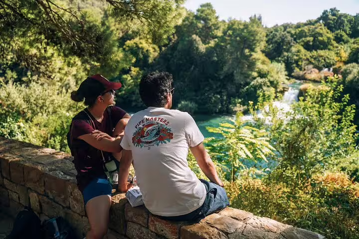 Couple resting at a viewpoint overlooking Krka Waterfalls on a private Krka tour with optional wine tasting