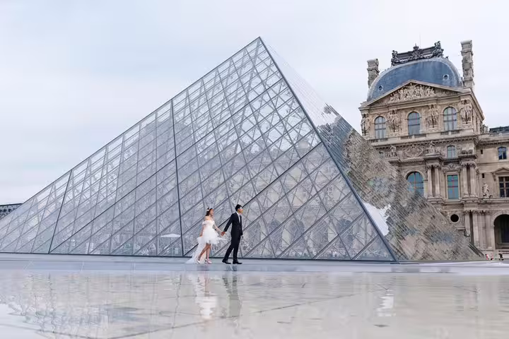 Couple walking by the Louvre Pyramid in Paris, proposal photographer capturing elegant engagement photos