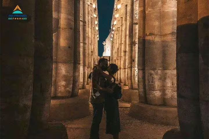 Couple in Luxor Temple colonnade at night, iconic stop on 8-day Nile cruise and Cairo tour Egypt