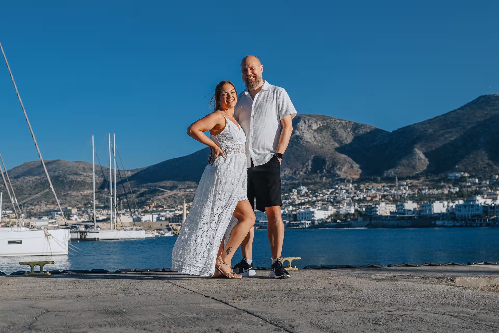 Couple posing by the marina with stunning mountain views at The Port of Hersonissos private photoshoot.