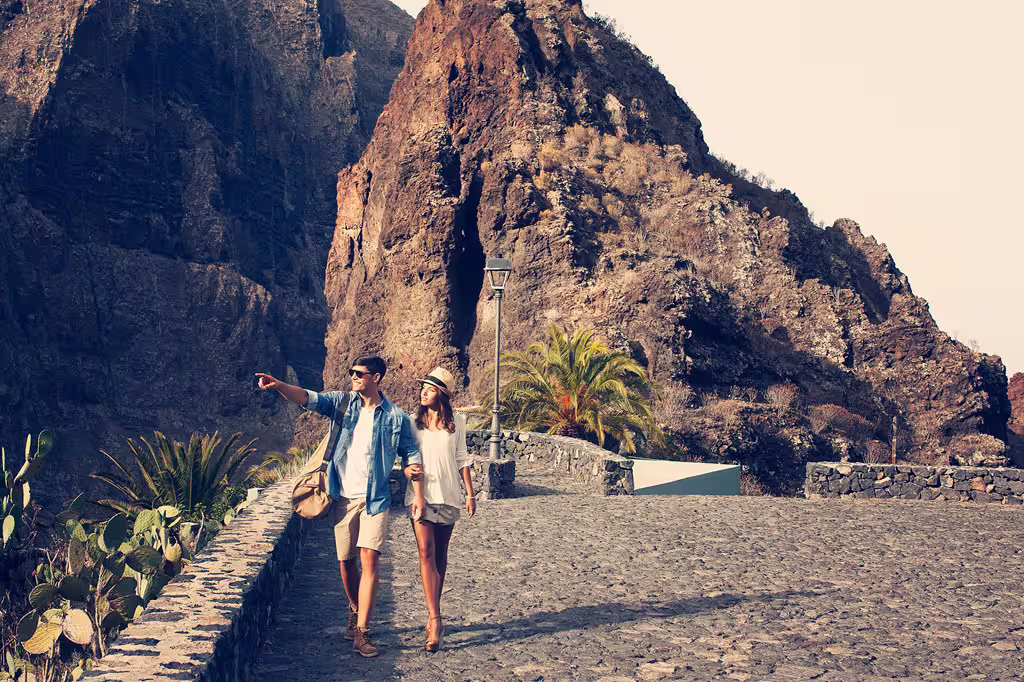Couple exploring the rugged beauty of Masca Gorge, Tenerife, with dramatic cliffs and lush vegetation.