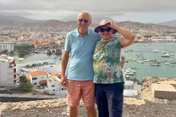 Couple enjoying panoramic view of Mindelo harbor on São Vicente Island tour, showcasing vibrant cityscape and marina.