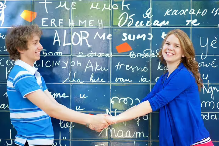 Couple holding hands in front of Montmartre's Wall of Love during a Paris private full day tour, showcasing romantic Parisian sights.