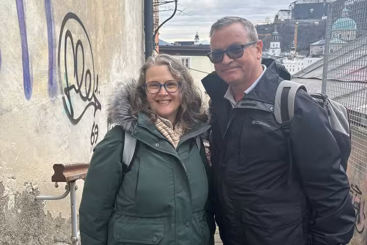 Couple smiling on Mozart Mystery Walk in Salzburg Old Town with historic cityscape behind