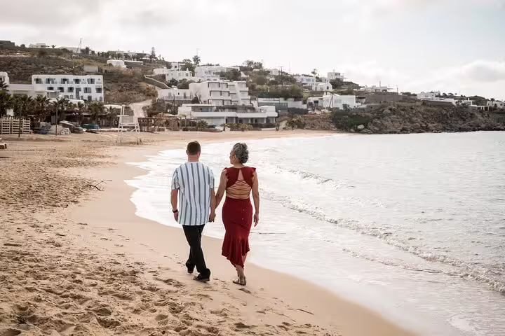 Couple walking along Mykonos beach at sunset during private photoshoot with professional photographer