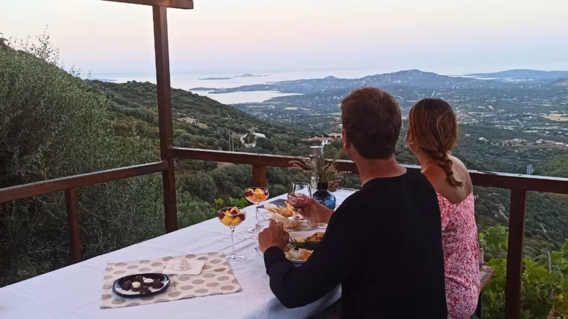 Couple enjoys gourmet tasting with panoramic views over Olbia's scenic landscape during myrtle-making tour.