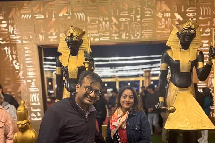Couple posing with Egyptian statues during Nile Cruise Dinner with Tanura Show experience.
