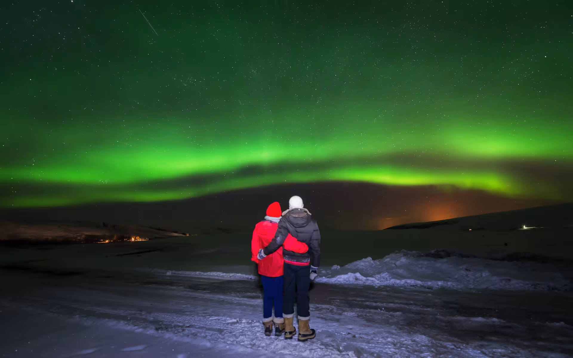 Couple embraces under the spectacular Northern Lights in Reykjavík, creating a romantic and unforgettable experience.