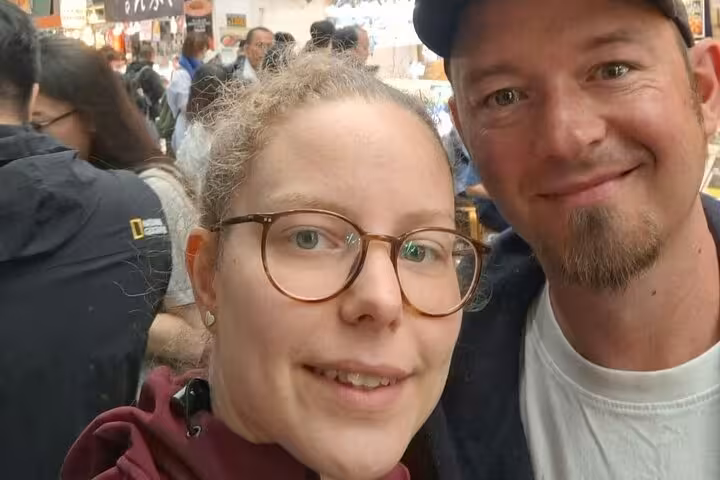 Couple smiling at a busy Osaka food market during a self-guided walking tour