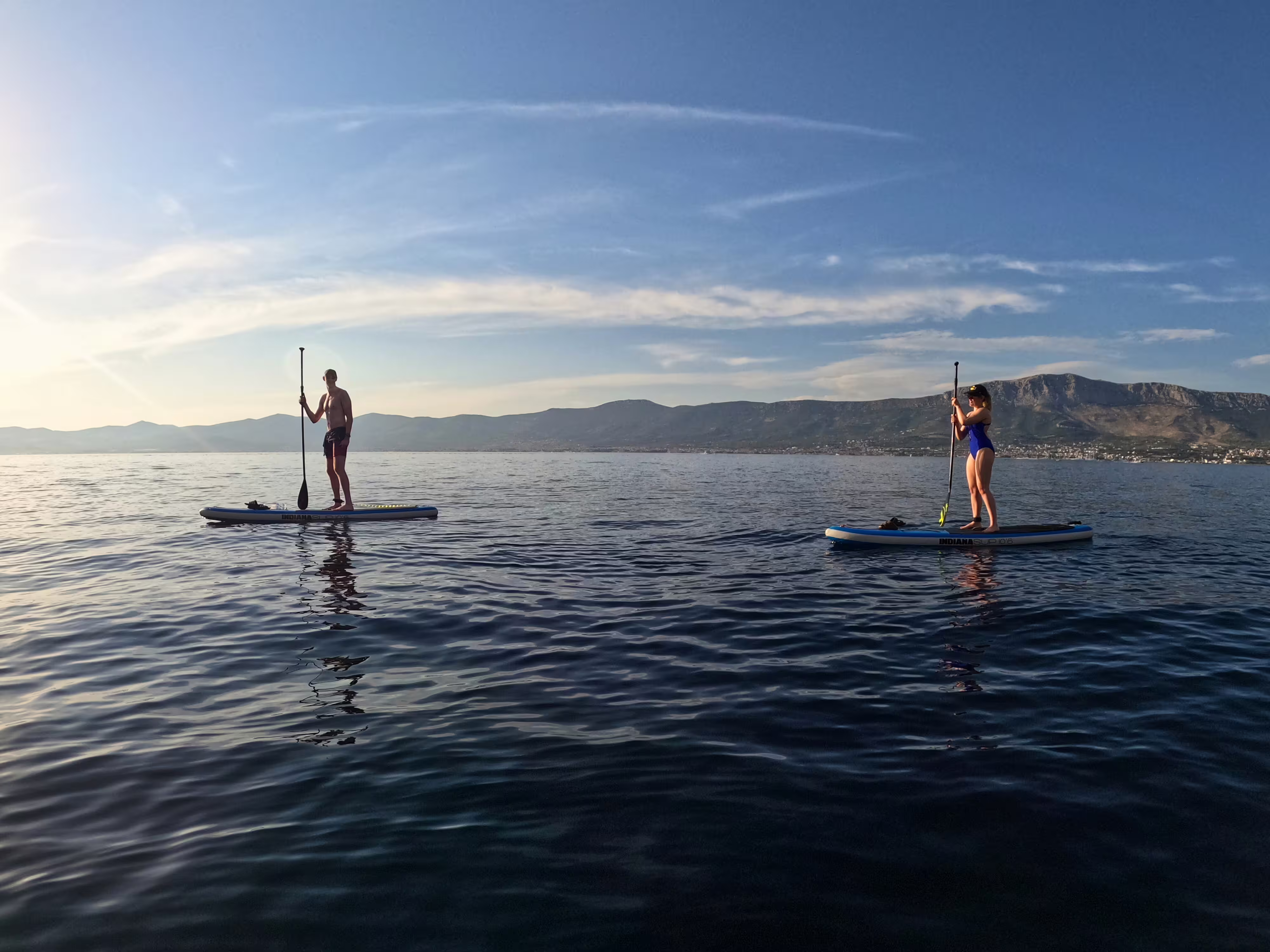 Couple paddleboarding on a calm Adriatic morning near Split, Croatia, with mountain views on a guided SUP tour