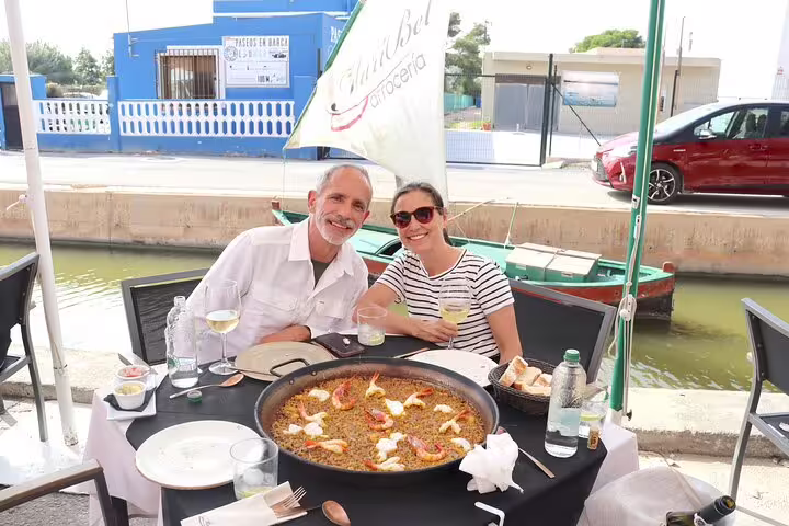 Couple enjoying authentic paella by the Albufera canal during a serene private day trip with boat ride and nature trek.