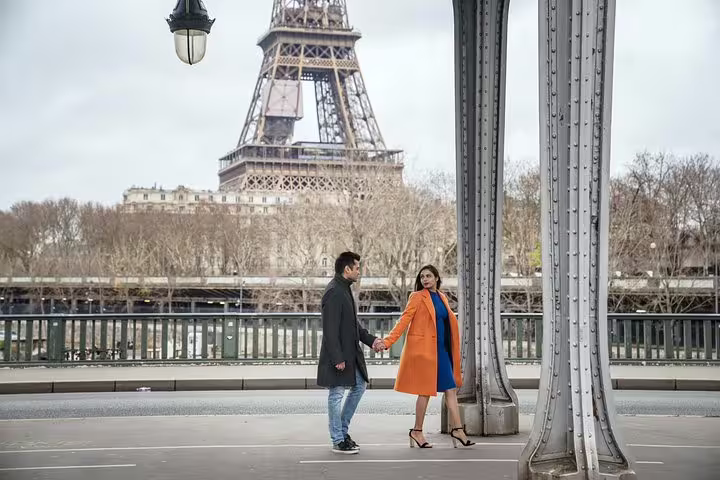 Couple holding hands on a Paris bridge with Eiffel Tower view during private travel photographer tour