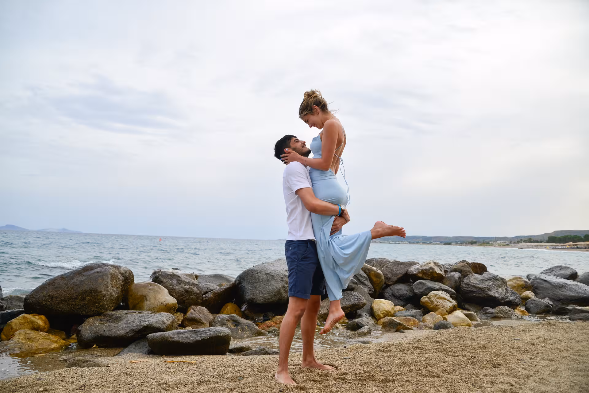 Couple enjoying a joyful moment by the rocky shore at Heraklion Venetian Port, highlighting a private photoshoot service.