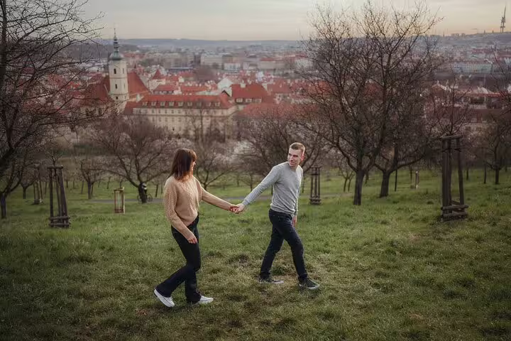 Couple walking hand in hand in a scenic park overlooking Prague's historic architecture on a private photoshoot.