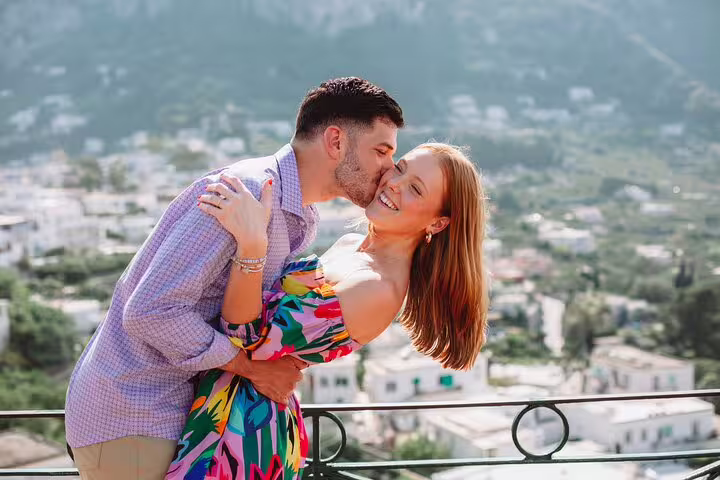 Smiling couple posing on a balcony with stunning Naples skyline during a private photoshoot.
