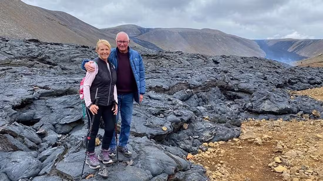 A couple standing on a fresh lava field in Iceland, posing for the camera