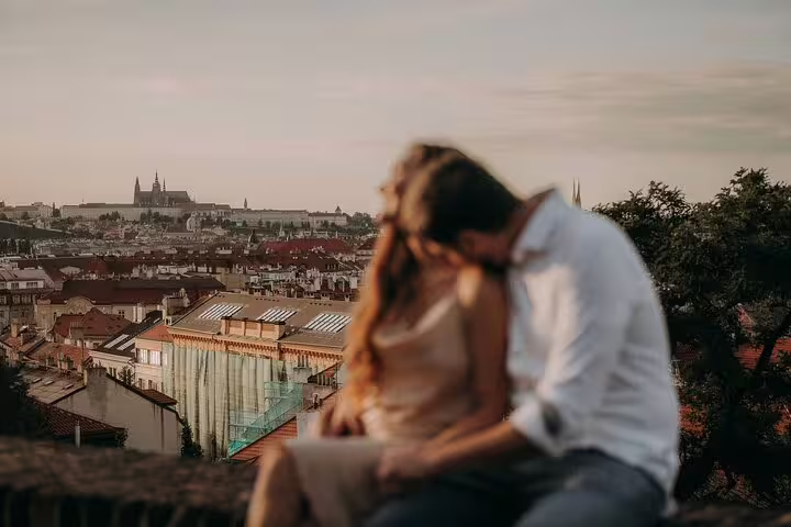 Couple embracing with panoramic view of Prague Castle during a professional photoshoot at sunset.
