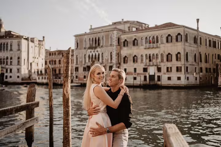 Couple embraces on a Venice dock with historic buildings in the background during a private water taxi tour.