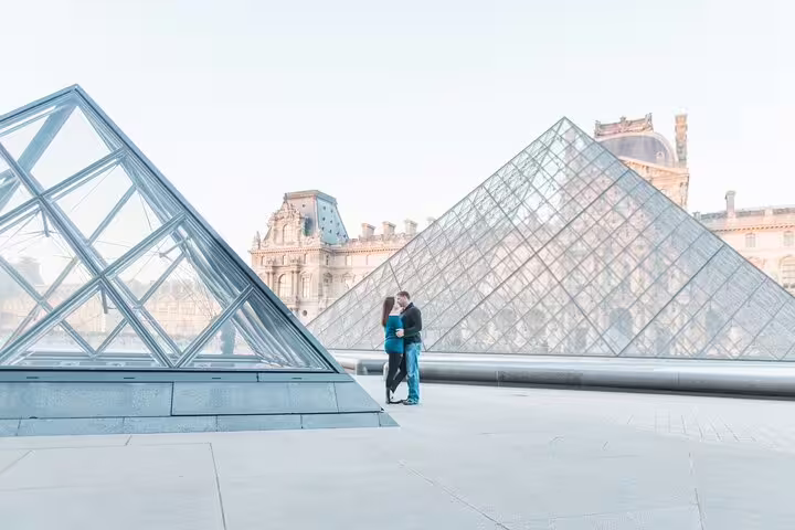 Couple embracing in front of the Louvre glass pyramids during a professional photoshoot in Paris