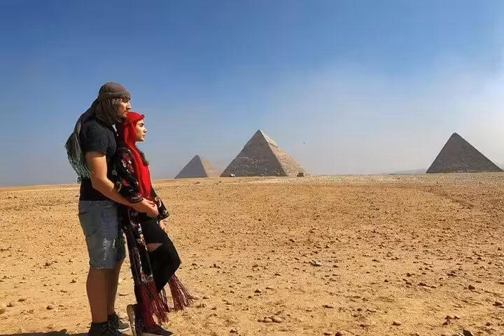 Couple in desert attire facing the pyramids on a private Sakkara desert safari excursion from El Sokhna Port