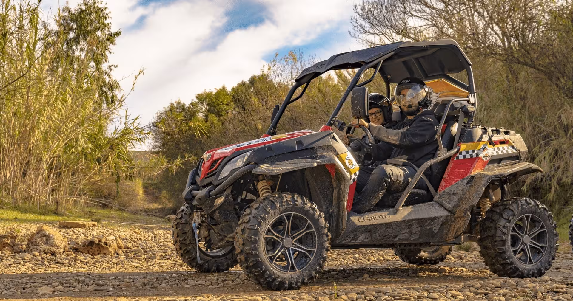 Couple driving a red off-road buggy on a rocky dirt trail during a half-day guided adventure tour through scenic countryside.