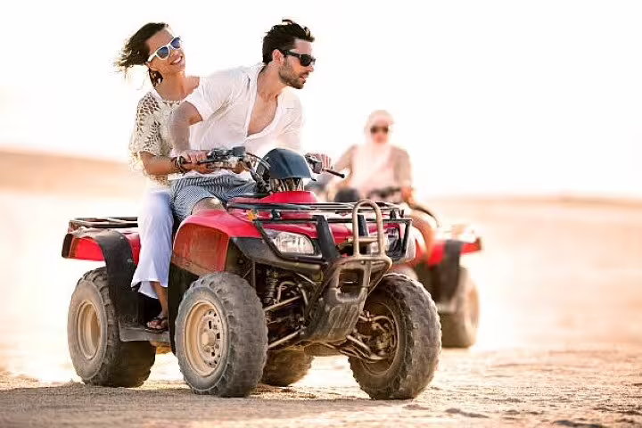 Couple riding a red quad bike in Hurghada desert, part of ATV safari adventure tour with camel ride option