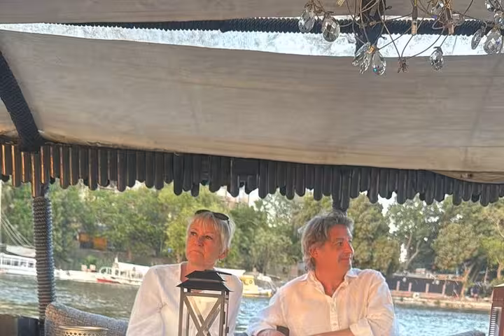 Couple relaxing under shaded felucca deck on the Nile River in Cairo during scenic sail with pickup