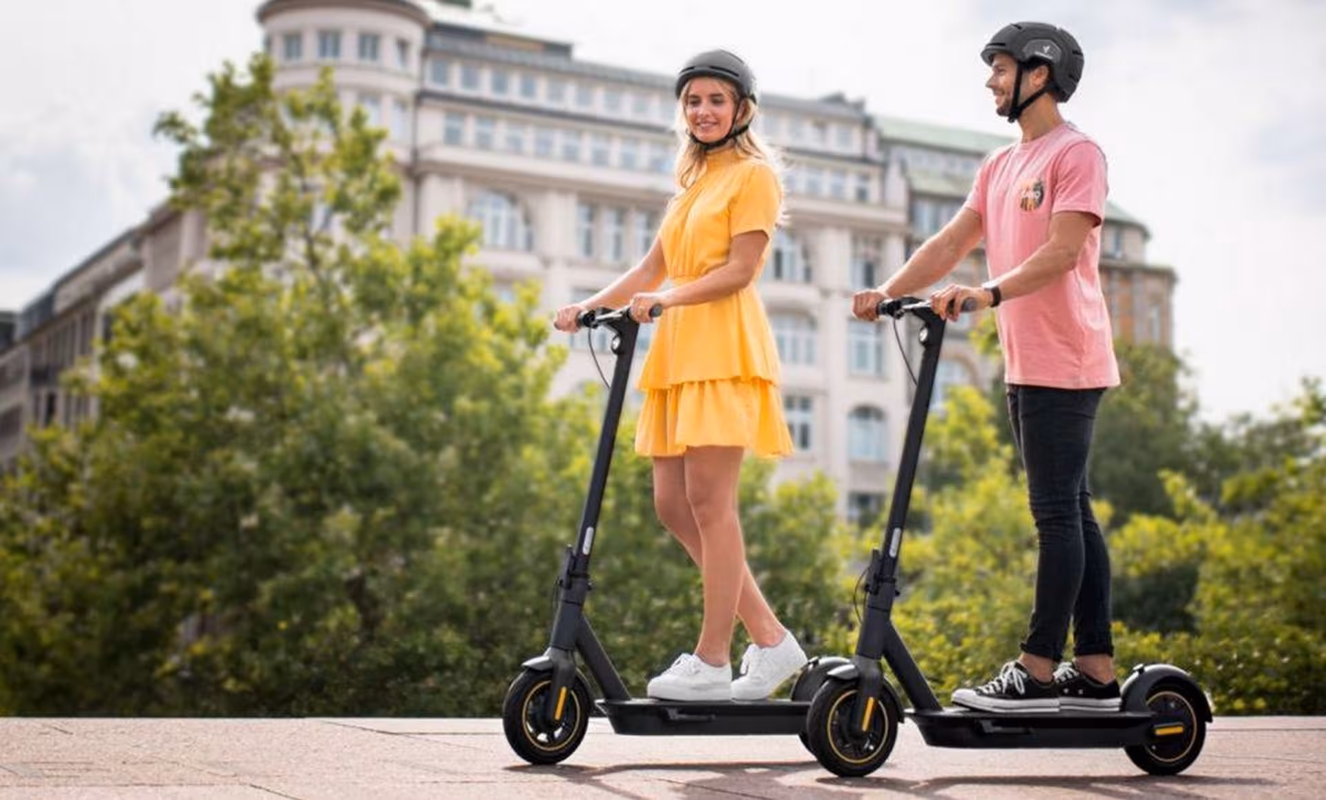 Couple riding e-scooters through scenic Krakow with historic architecture in the background.