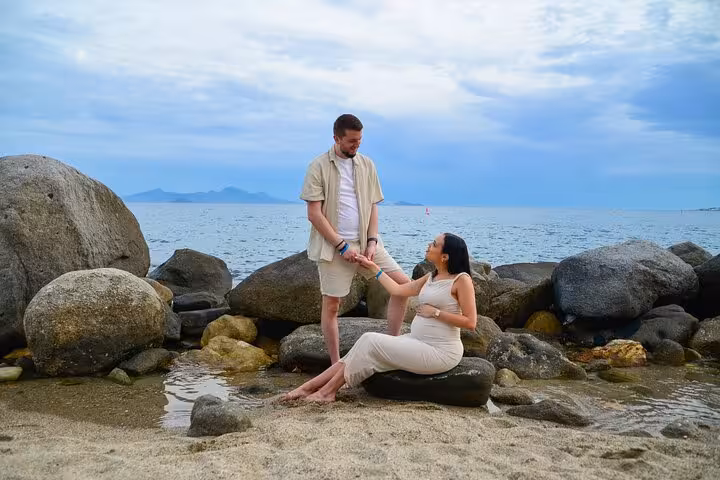 Couple enjoying a romantic moment on Analipsi beach, surrounded by rocks and serene sea views, perfect for a private photoshoot.