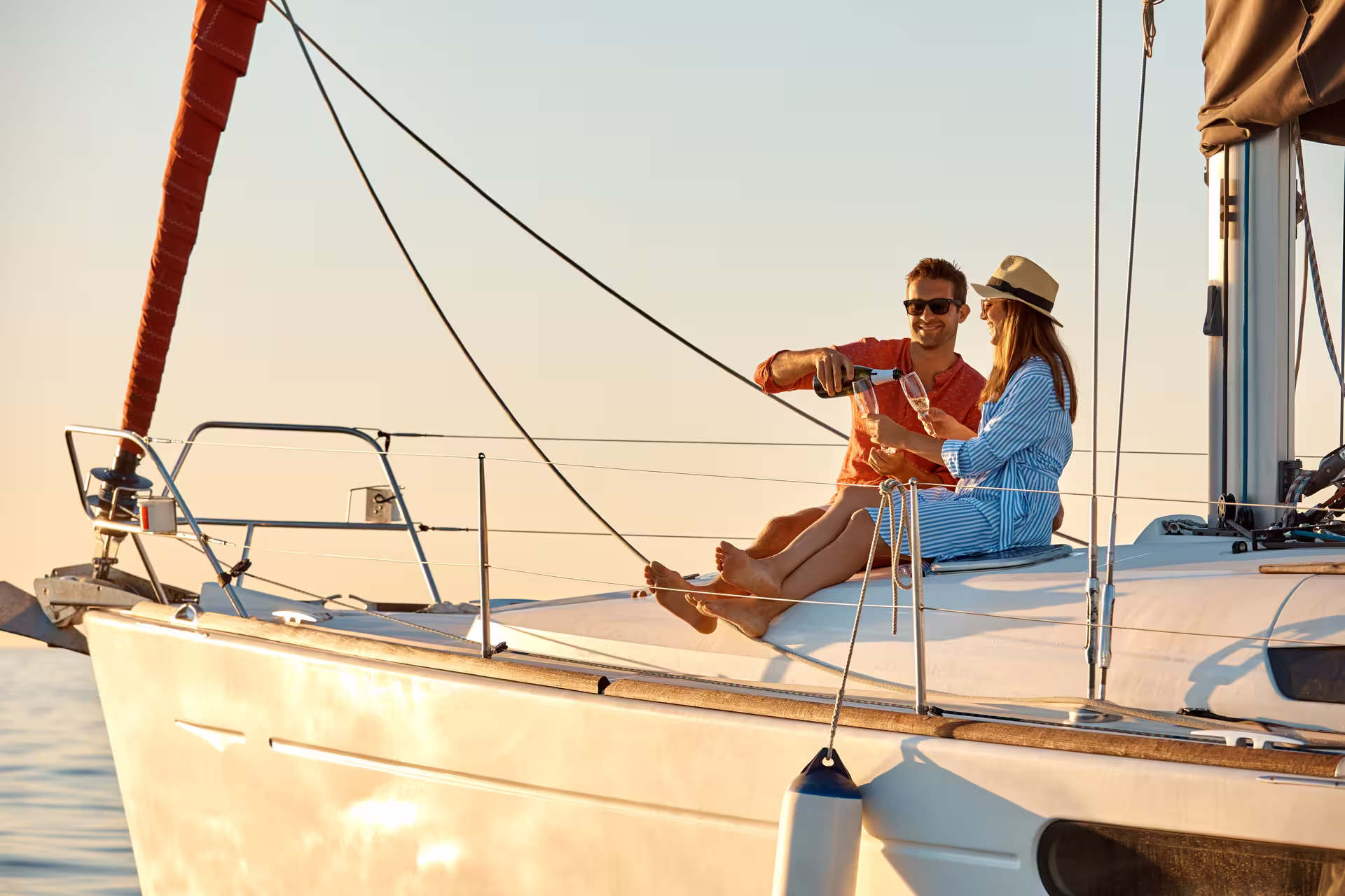 Couple enjoying a romantic 2-hour sailboat experience, sipping champagne with stunning views, perfect for a relaxing getaway.