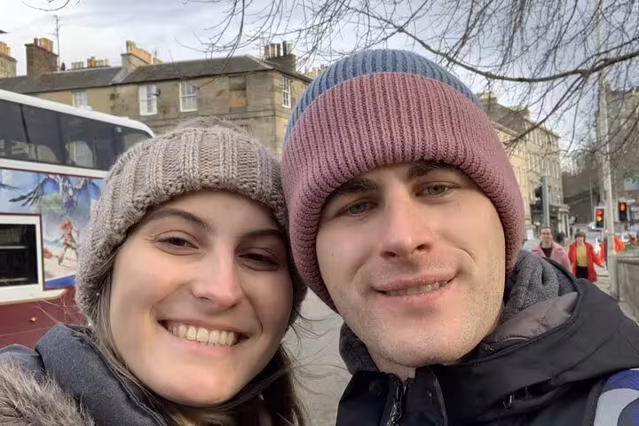 Smiling couple in knit hats taking a selfie on an Edinburgh street in winter