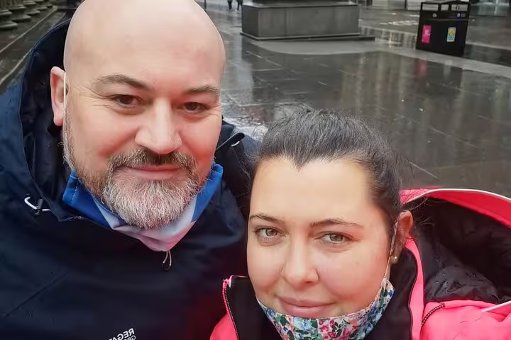 Couple taking a selfie outdoors in Glasgow on a rainy day during a romantic walking tour