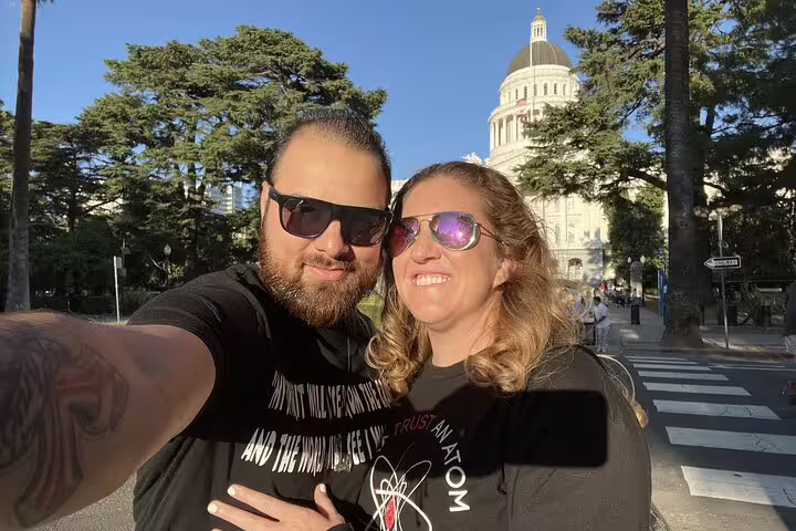 Couple taking a selfie smiling in front of Sacramento Capitol building on a sunny day