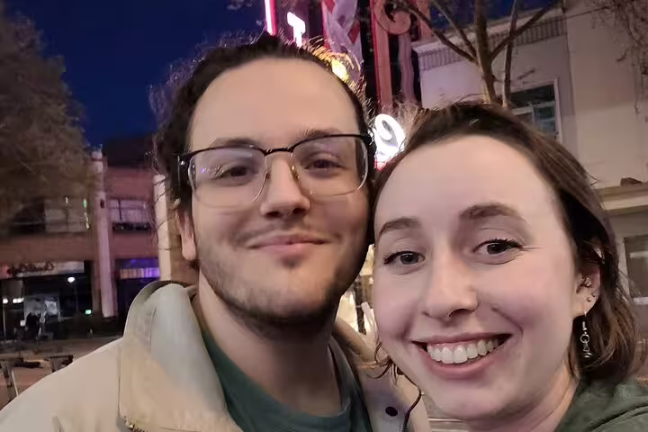 Smiling couple taking a selfie at night in downtown Sacramento with neon lights in background