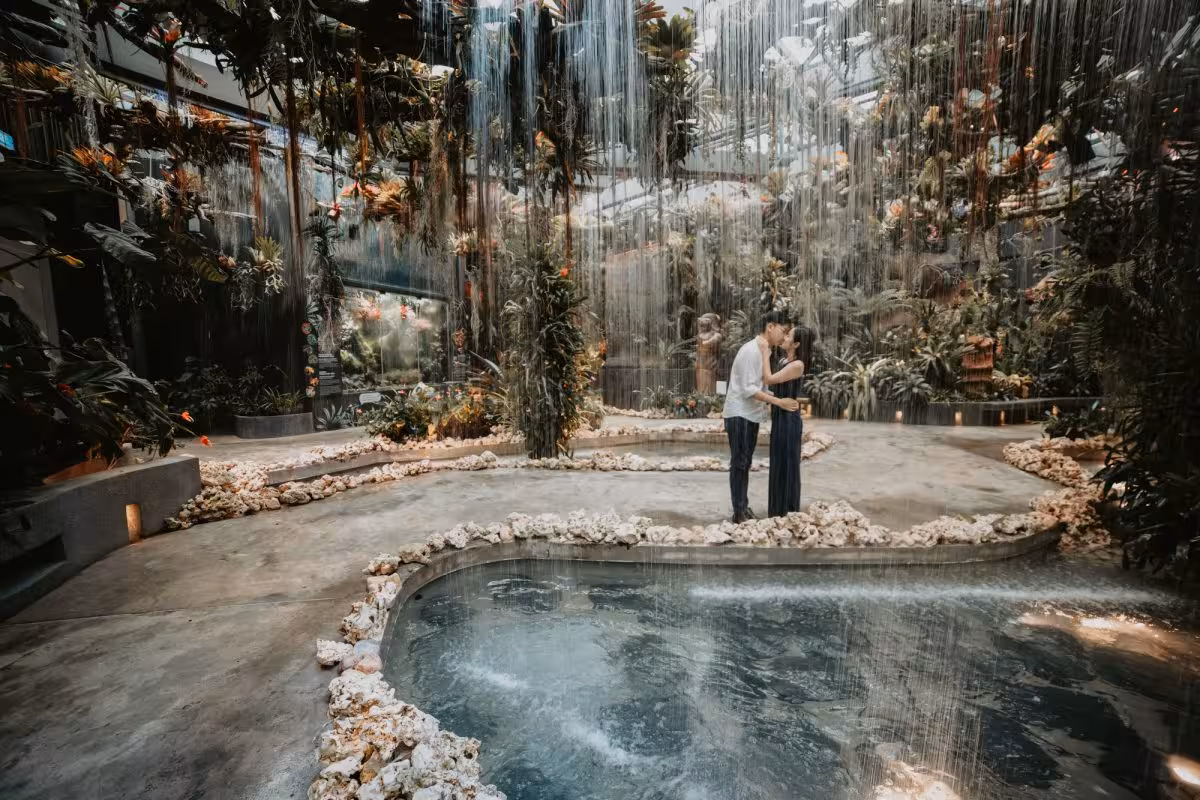 Couple sharing a romantic moment under a waterfall in a captivating private photoshoot setting in Singapore.