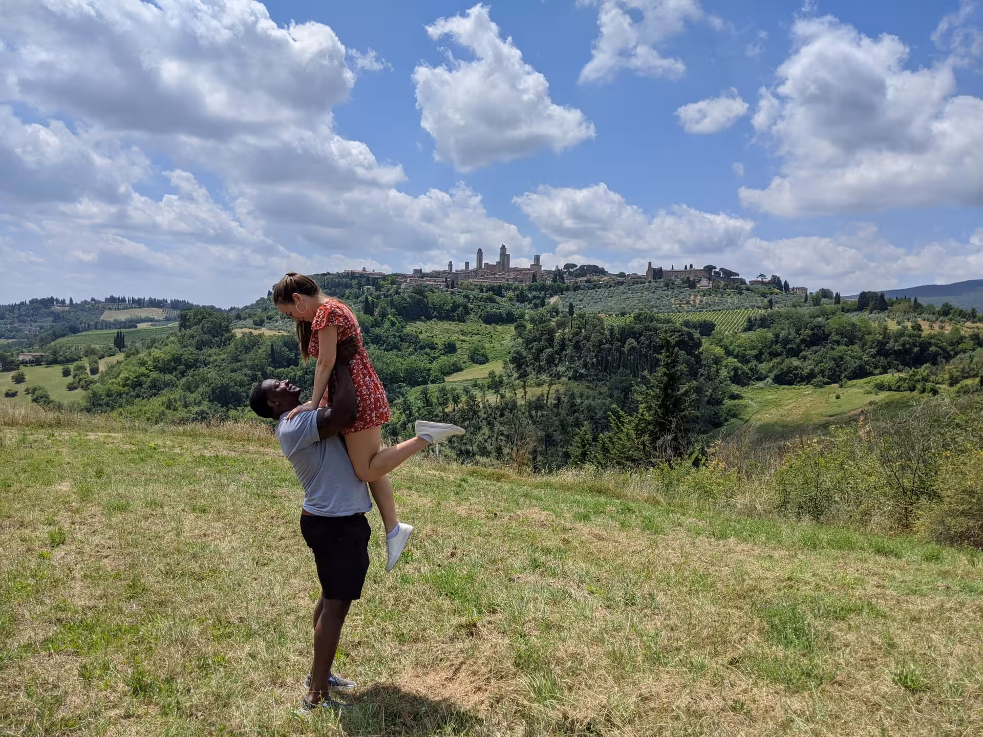 Couple enjoying scenic view of San Gimignano's towers and rolling Tuscan hills on a private tour from Florence.