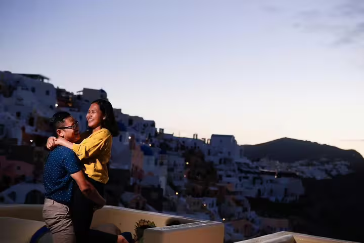 Playful couple embracing with a picturesque Santorini evening skyline on a personal photography tour.