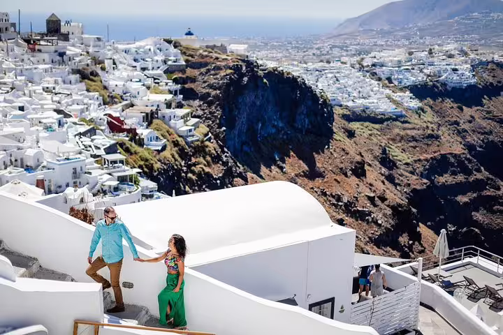 Couple exploring the picturesque whitewashed buildings and cliffs of Santorini, Greece on a sunny day.