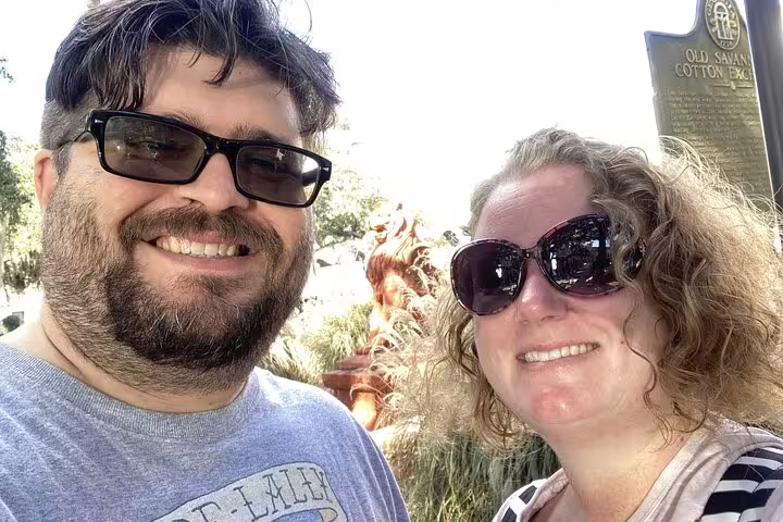 Couple smiling at Old Savannah Cotton Exchange historic marker on Savannah waterfront