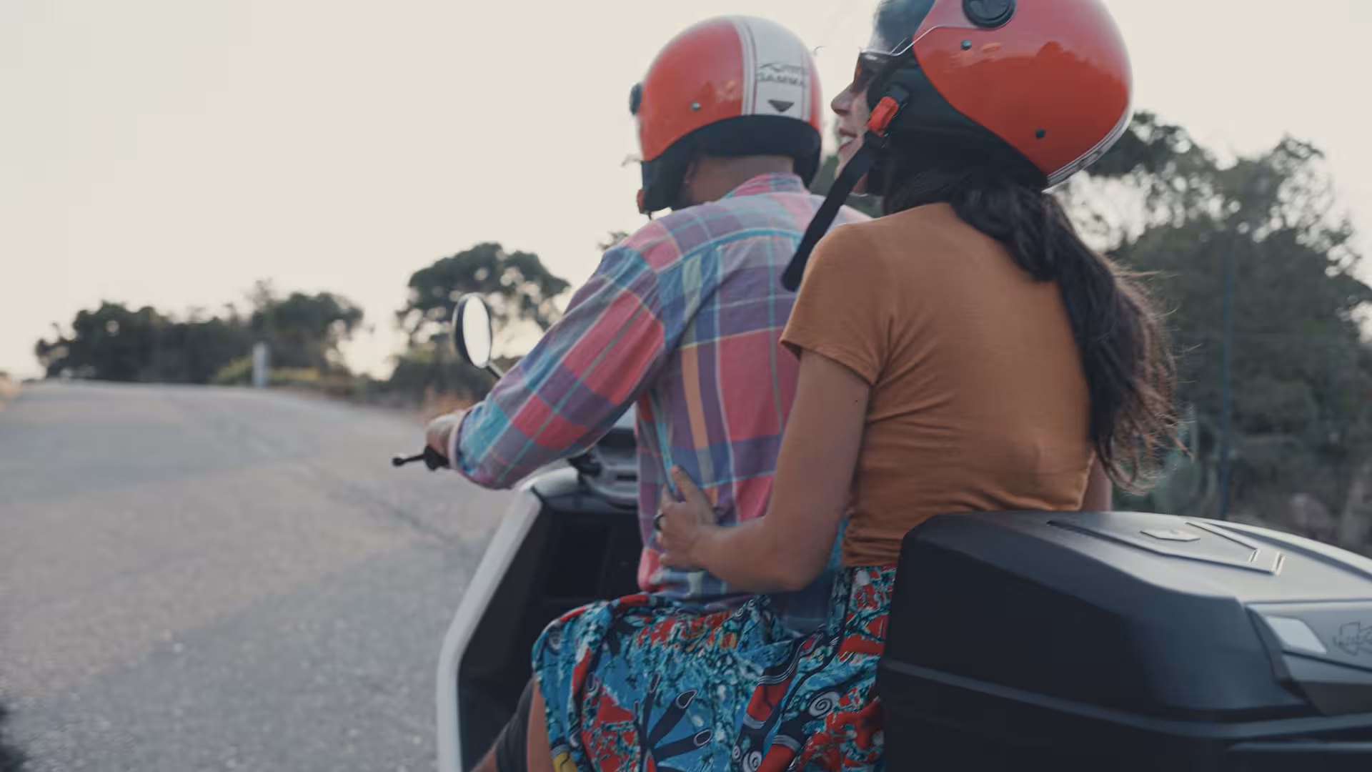 Couple riding a scooter on a scenic road in Olbia, Italy, perfect for an adventurous rental experience.