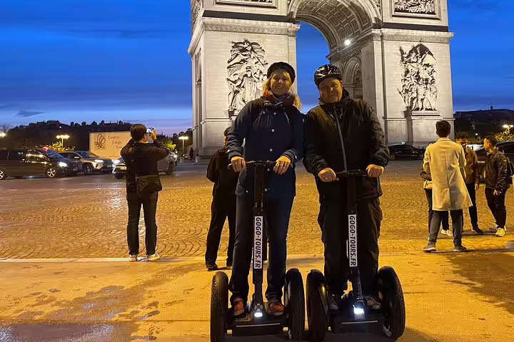 Couple on Segways by illuminated Arc de Triomphe, Paris night Segway tour with local guide in winter