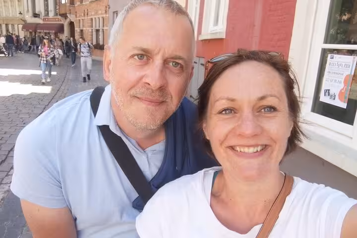 Couple smiling on a cobblestone street in historic Bruges during a self-guided walking tour