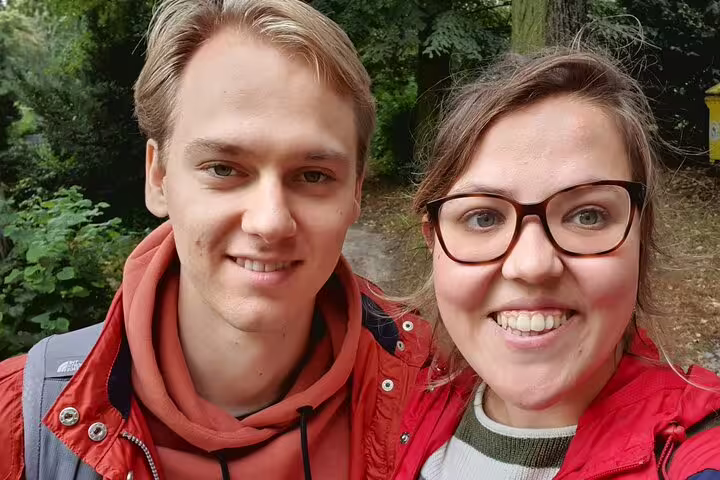 Two smiling young adults in red jackets on a self-guided walking tour in Kreuzberg Berlin