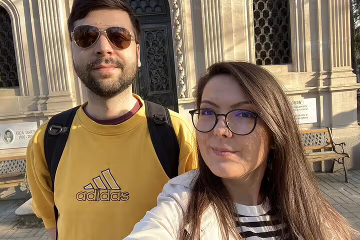 Couple taking a selfie in front of Bellu Cemetery ornate entrance gate in Bucharest